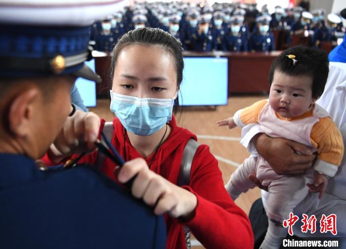 新消防員楊振的妻子彭莉與女兒現(xiàn)場(chǎng)見(jiàn)證丈夫加入“火焰藍(lán)”的神圣時(shí)刻。　劉忠俊 攝